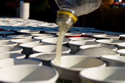 Close-up of bottle pouring drink in disposable cup