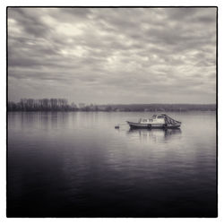 Boats in sea against cloudy sky