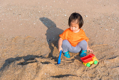 High angle view of boy playing with toy on sand