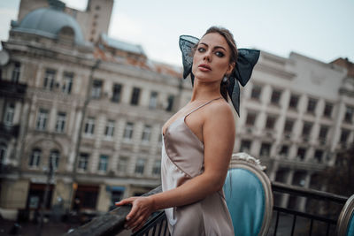 Portrait of beautiful woman standing against buildings in city