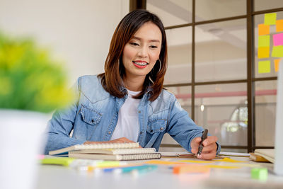 Low angle view of smiling businesswoman working at desk in office