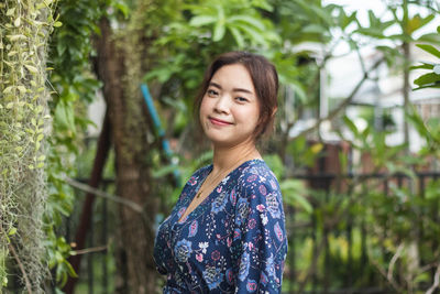 Portrait of young woman standing against trees