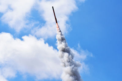 Low angle view of smoke emitting from equipment against blue sky