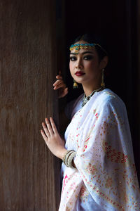 Portrait of beautiful woman in sari standing by wall