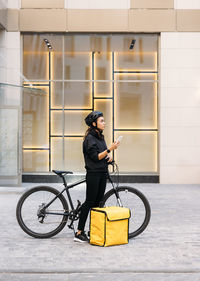 Side view of man holding bicycle