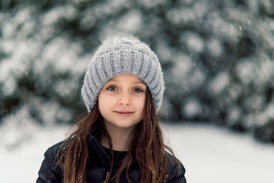 Close-up portrait of girl smiling while standing on field during snowfall