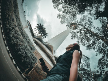 Low section of woman standing on hammock against trees