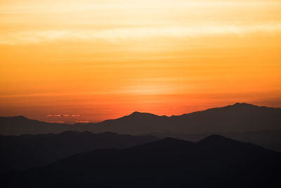 Scenic view of silhouette mountains against romantic sky at sunset