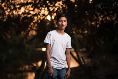 Portrait of teenage boy standing against trees
