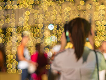 Defocused image of woman photographing lights