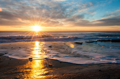 Sun shining through clouds over sea