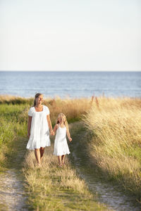 Mother with daughter walking at sea