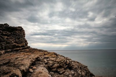 Rock formation by sea against sky