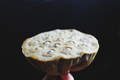 Close-up of hand holding apple against black background