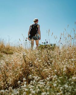 Rear view of woman standing on field against clear sky during sunny day