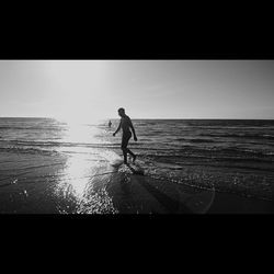 Silhouette man standing on beach against clear sky