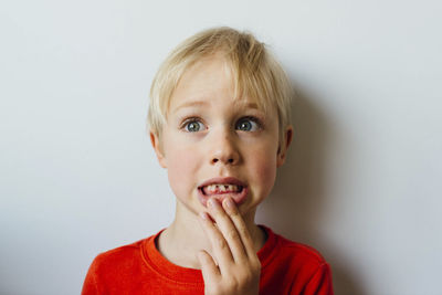 Close-up of cute boy showing teeth while standing against wall at home