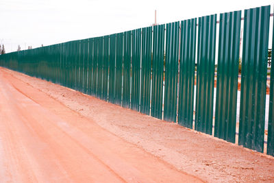 Footpath by fence against sky