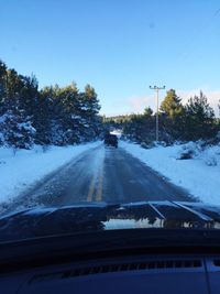 Car on road against clear sky seen through windshield