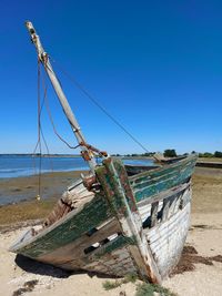 Abandoned fishing boat on beach against clear sky