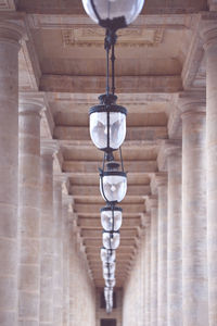 Low angle view of electric lamp hanging on ceiling in corridor