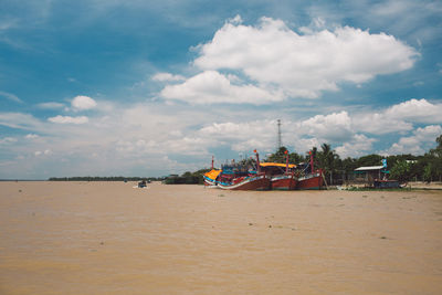 Fishing boats moored in river against sky