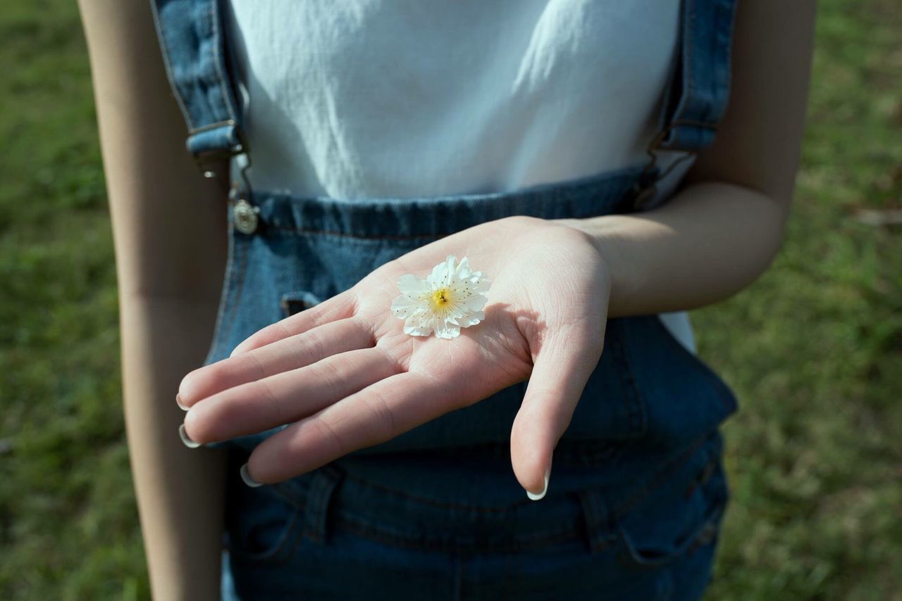 person, holding, lifestyles, part of, leisure activity, focus on foreground, midsection, human finger, close-up, cropped, unrecognizable person, low section, showing, flower, personal perspective