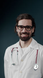 Portrait of smiling doctor against colored background