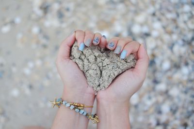 Cropped hands of woman holding sand