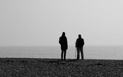 Rear view of people standing at beach