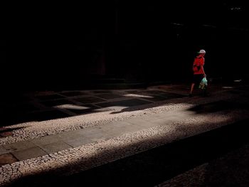 Rear view of man walking on road at night