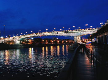 Illuminated bridge over river at night