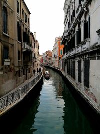 Canal in city against clear sky