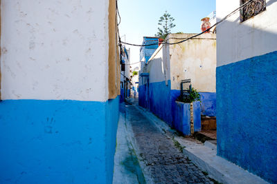 Clothes drying on alley amidst houses against sky