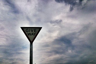 Low angle view of sign board against cloudy sky