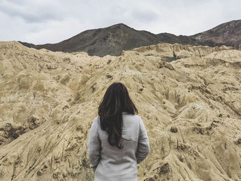 Rear view of woman looking at mountains against sky