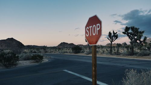 Road sign by street against sky