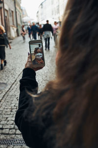 Young woman having video call talking while walking downtown in the evening wearing the face mask
