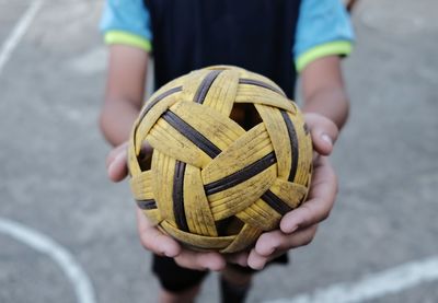 Close-up of person holding takraw ball against blurred background