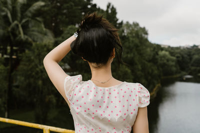 Rear view of woman standing against trees