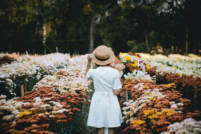 Rear view of woman standing by flowering plants