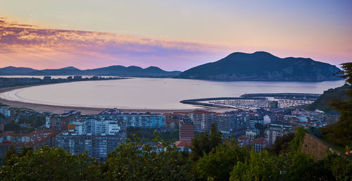 High angle view of buildings by sea against sky during sunset