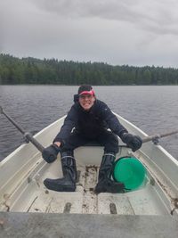 Portrait of young woman sitting in lake against sky