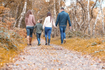 Rear view of people walking in forest