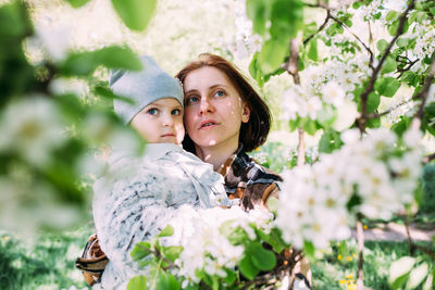 Portrait of young woman standing against tree