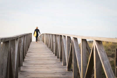 Rear view of woman walking on footbridge