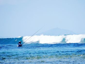 Man surfing in sea against clear sky