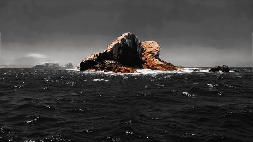 Rock formation in sea against sky