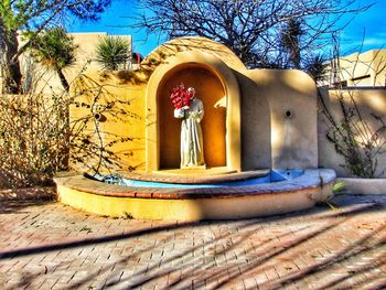 View of built structure by bare trees against sky