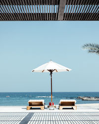 Wind turbines on street by sea against clear sky